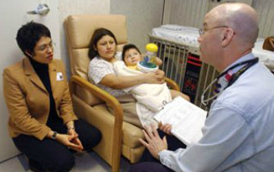Un docteur dans sa clinique avec une patiente, son bébé, et une interprète.